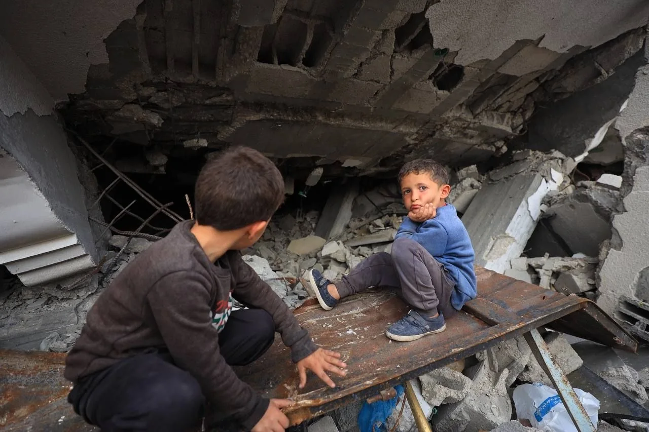 Children sitting among the remains of a damaged building