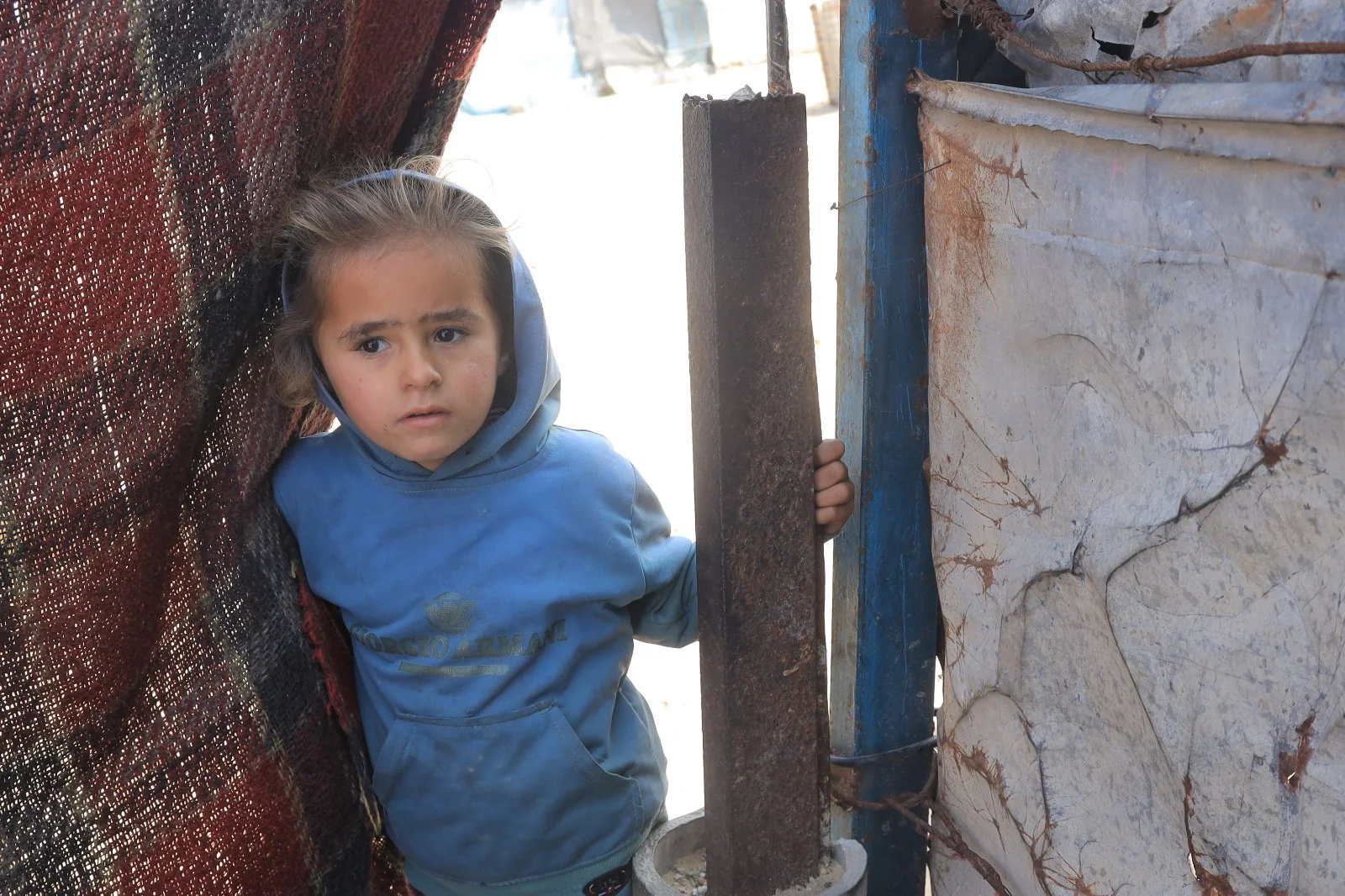 A young girl standing at the entrance of a temporary shelter